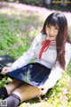 A woman in a school uniform sitting in a field of flowers.