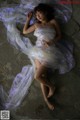 A woman in a white dress laying on the ground.