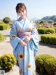 A woman in a blue kimono standing in a garden.