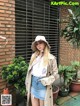 A woman standing in front of a brick building wearing a hat.