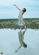 A woman in a gray dress standing in the water.