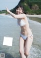 A woman in a white bikini standing in the water.