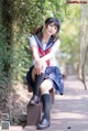 A woman in a school uniform sitting on a bench.