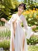 A woman in a white kimono posing in a garden.