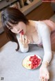 A woman sitting at a table with a plate of fruit.