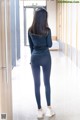 A woman in a black top and leggings standing in a hallway.