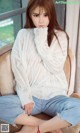 A woman sitting on a chair wearing a white sweater.