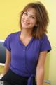 A woman in a purple shirt and black skirt posing for a picture.