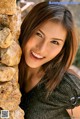 A beautiful young woman leaning against a stone wall.